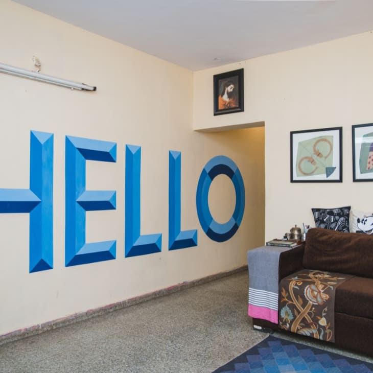 Living room with hand-painted wall art that says "HELLO" in large blue letters