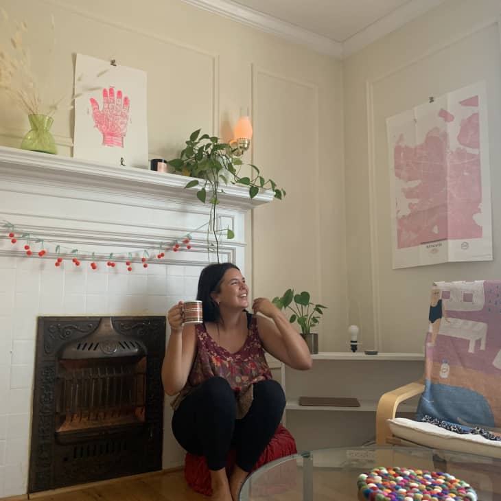 Woman sitting next to fireplace in living room with pink accents