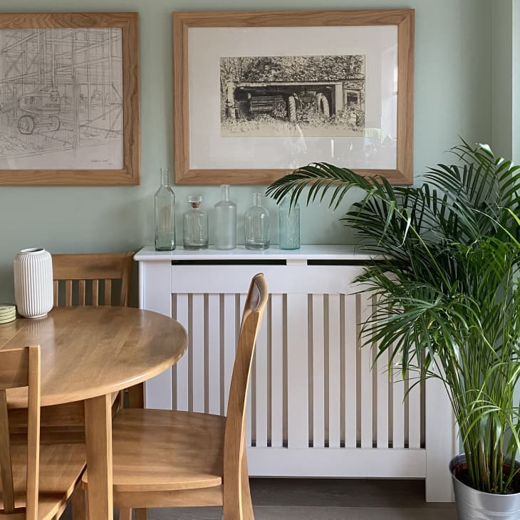 Dining area with light green walls, wooden table, and white sideboard