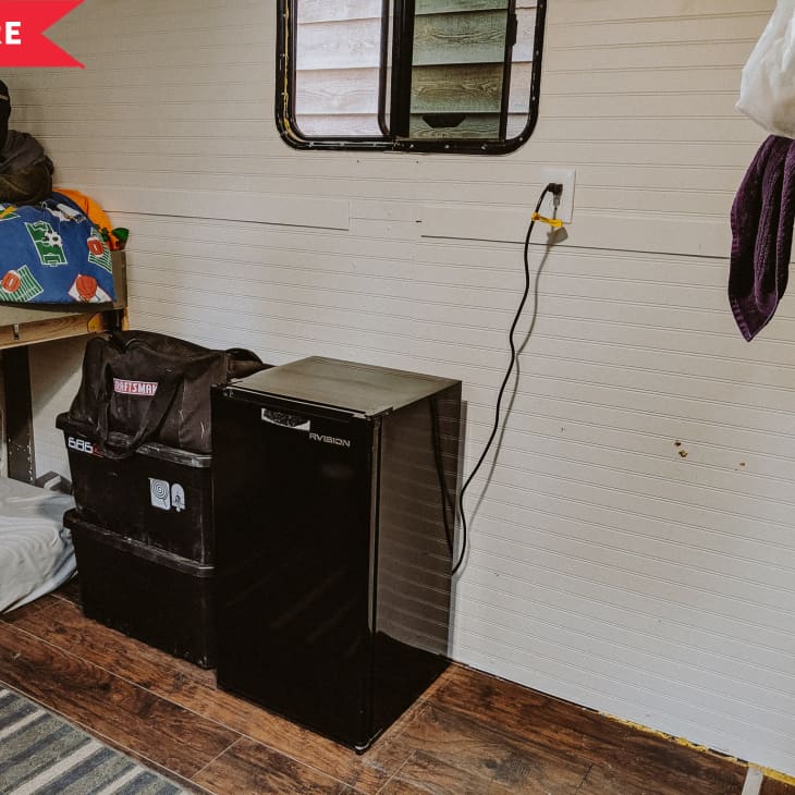 Before: Mini fridge next to large storage tubs in front of white wall