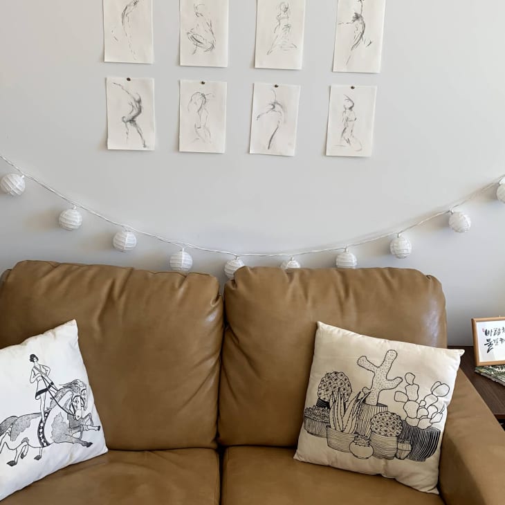 Leather loveseat with string lights and sketches on paper above