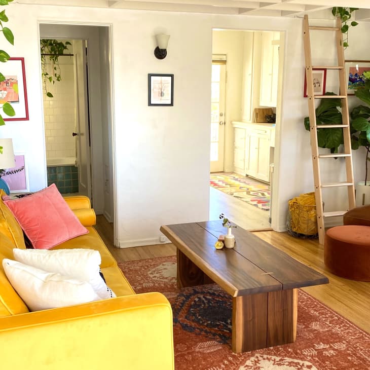 Living room with yellow sofa and ladder to upper-level loft