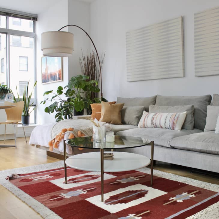 Living room with gray sofa, arched floor lamp, and red southwestern-style rug