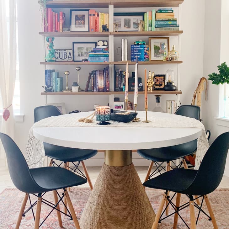 Round table with black chairs in front of shelf with colorful books