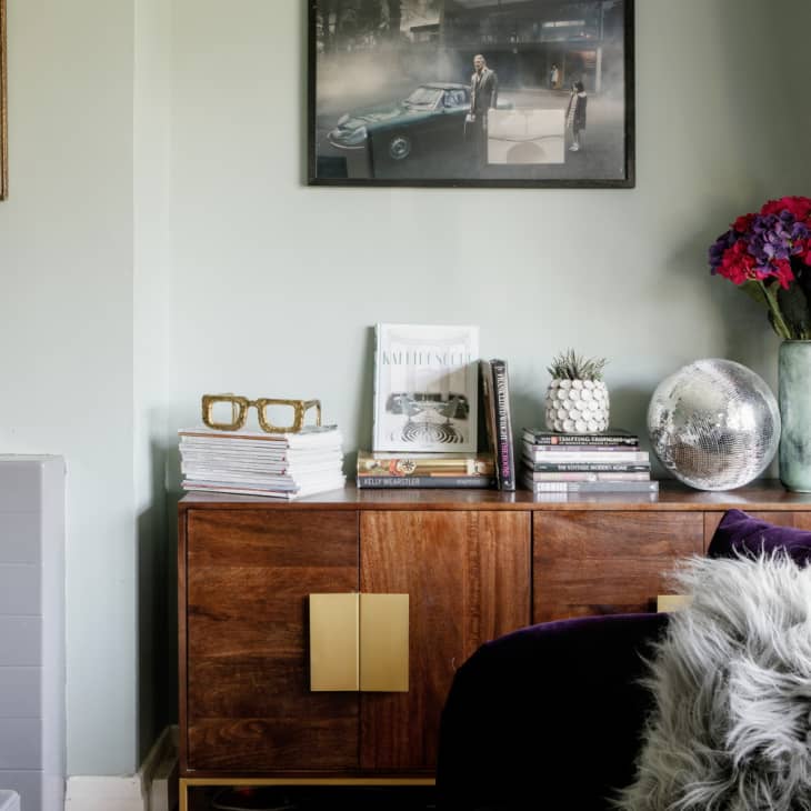 Living room credenza with books, disco ball, and vase of flowers on top