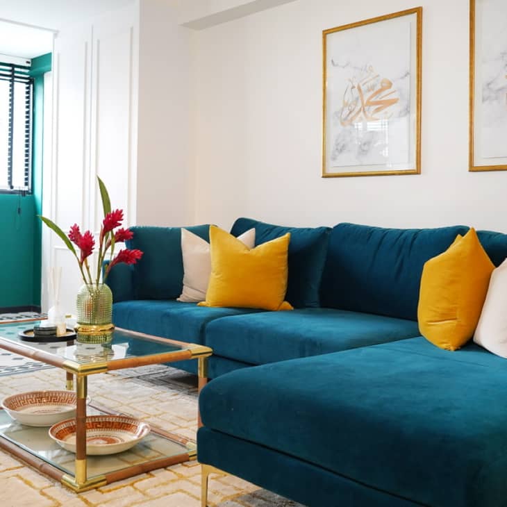Teal sofa with two large gold-framed art pieces above