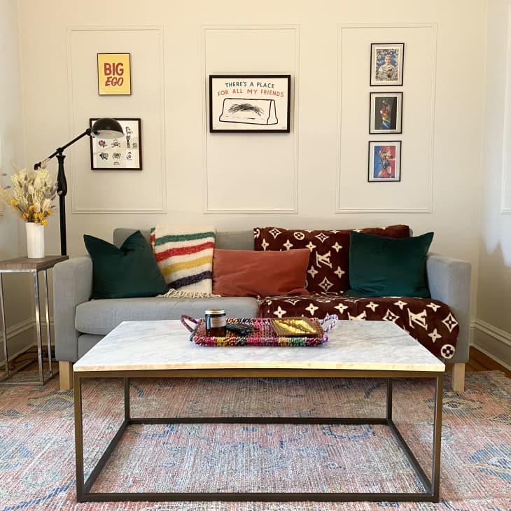 Gray sofa with throw pillows and blankets and rectangular coffee table in living area with molding on walls