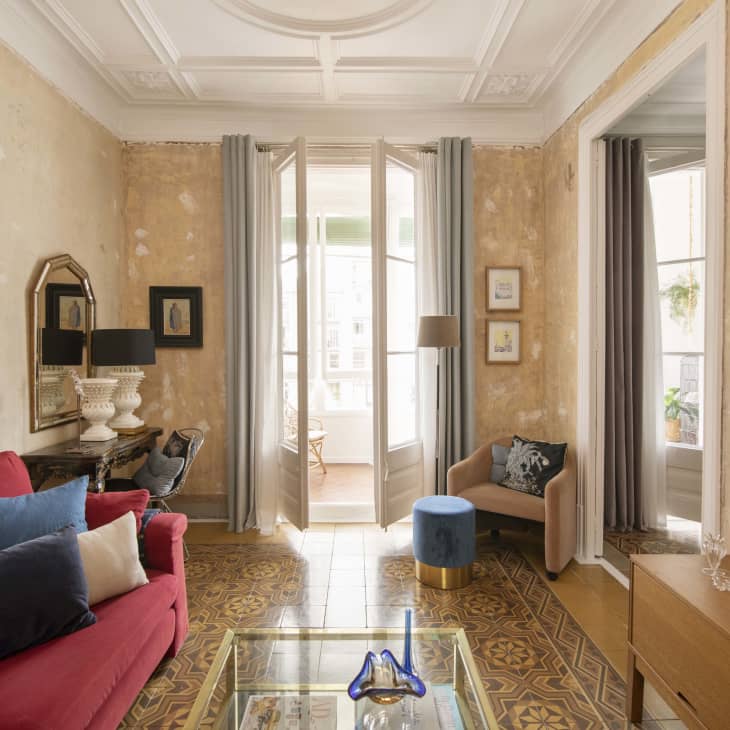 Living area with gold leafed wall, large french doors, and molding on ceiling
