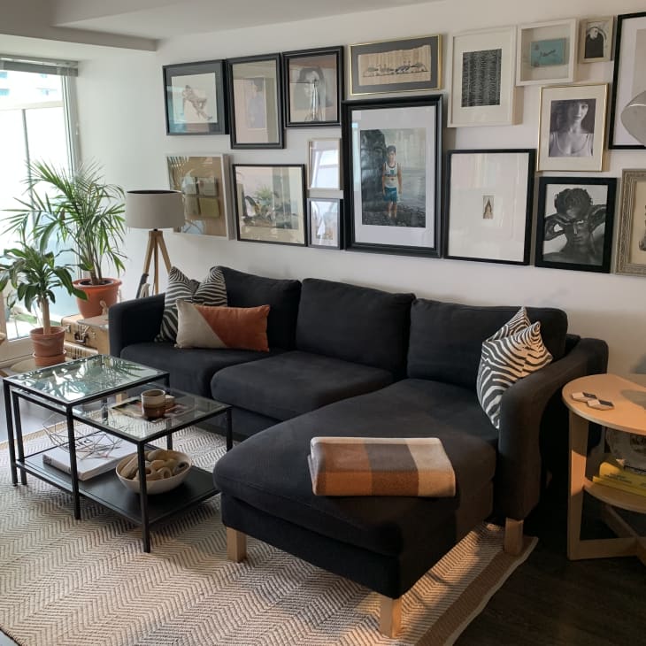 Gray sofa and neutral framed photos and artwork arranged in gallery wall above