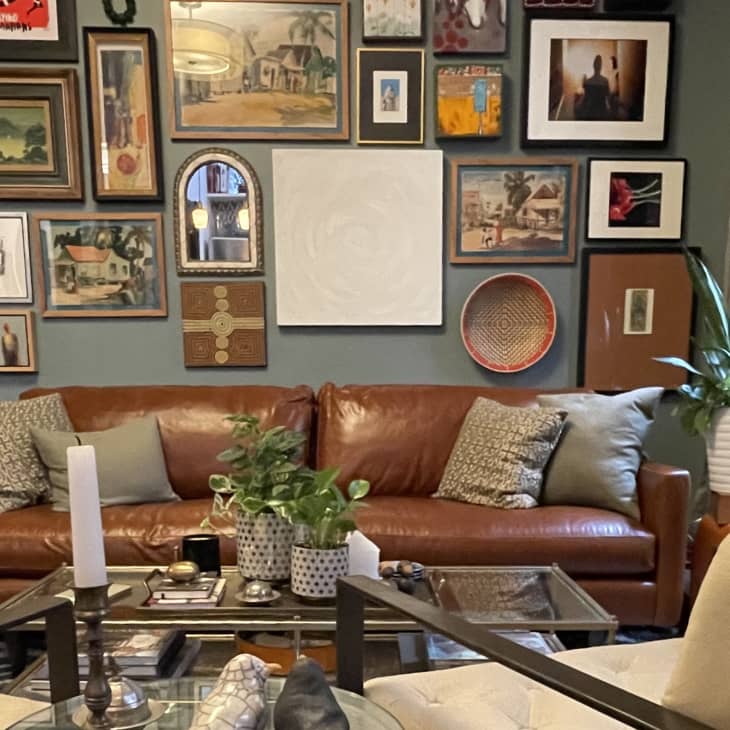 Leather sofa beneath lots of framed artwork hanging on gray wall