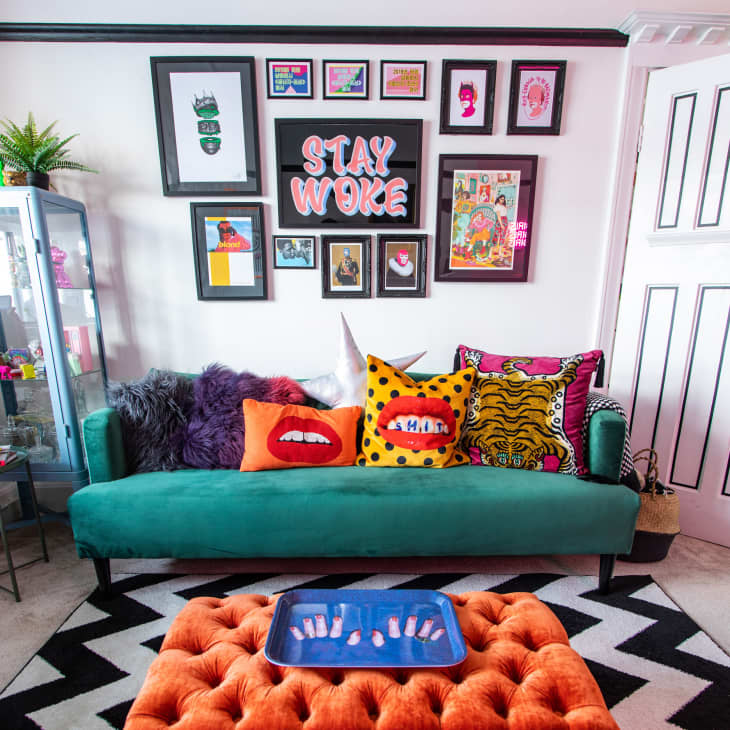 Colorful living room with green sofa, orange ottoman, chevron rug, and gallery wall behind sofa