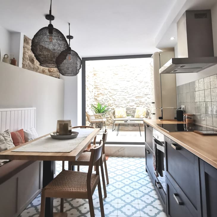 Modern kitchen with wooden countertops, patterned tile floor, pendant lights, and a dining area with bench seating.