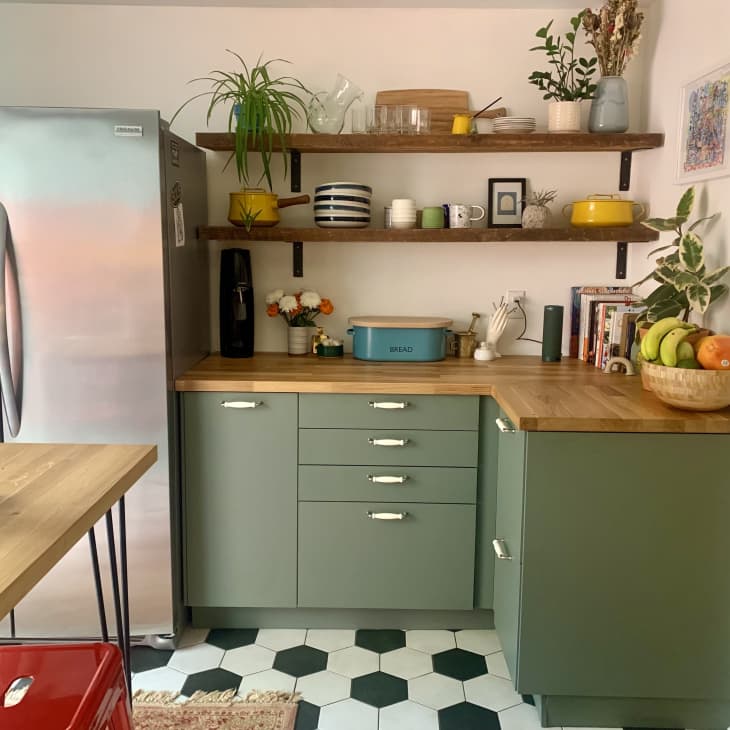 Kitchen with black and white flooring, green lower cabinets, and stainless steel fridge