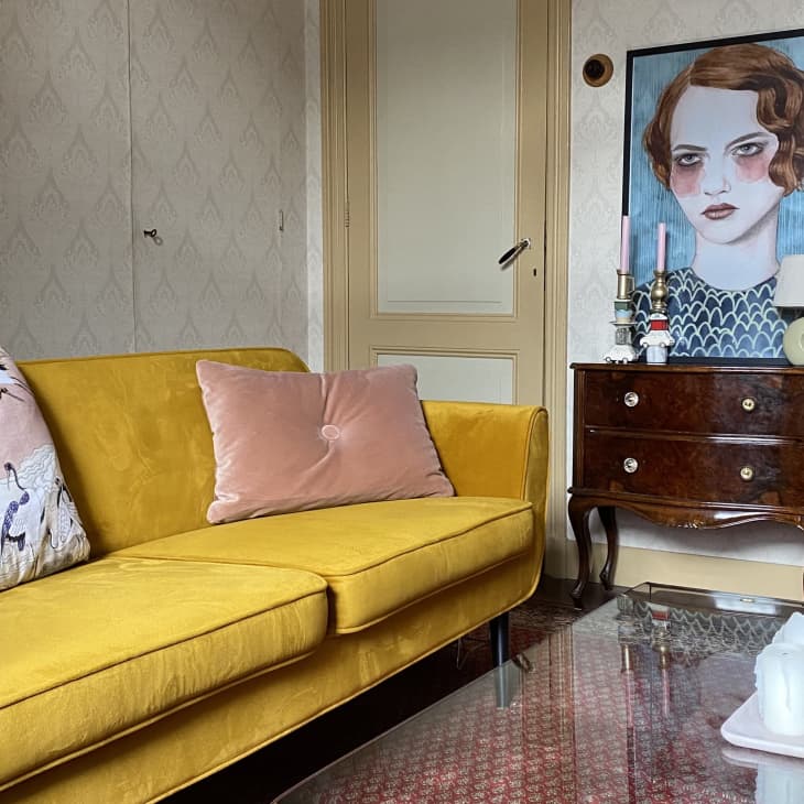 Living room with yellow sofa and large portrait artwork above antique buffet