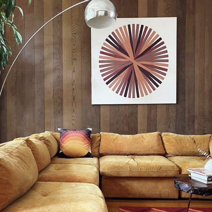 Gold velvet sectional in room with wood-paneled walls