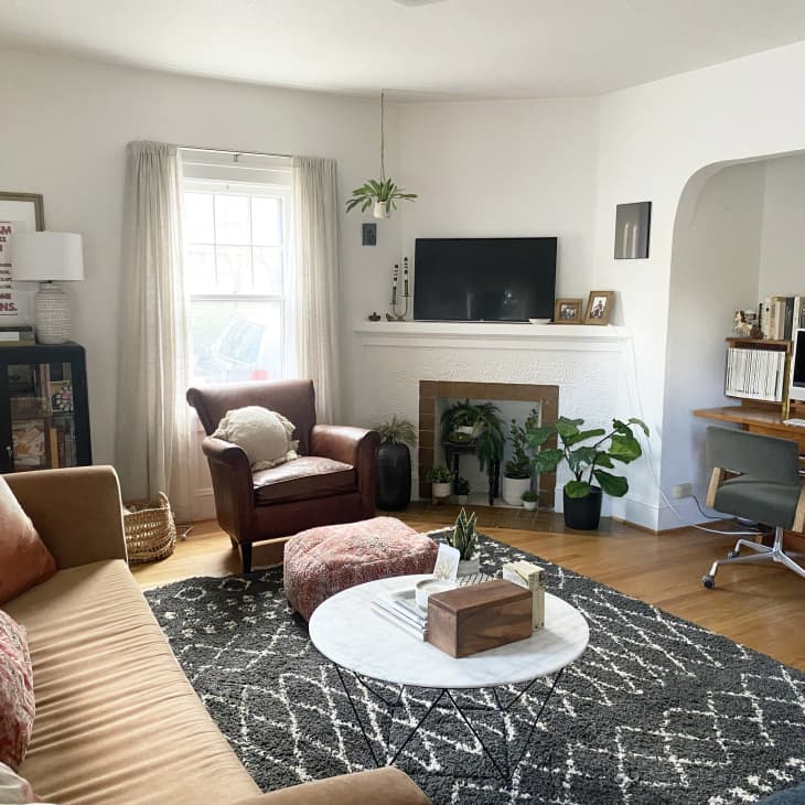 Modern comfortable living room with white walls, tan sofa, brown leather chair, and white marble coffee table