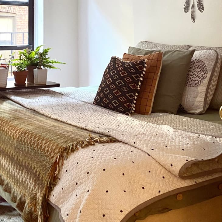 Bed layered with blankets in a small but bright white bedroom