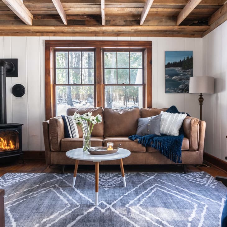 living room with brown couch and blue rug