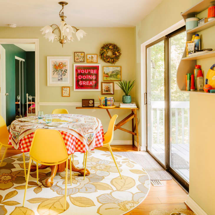 A dining room with a round table and yellow chairs on a round floral rug.