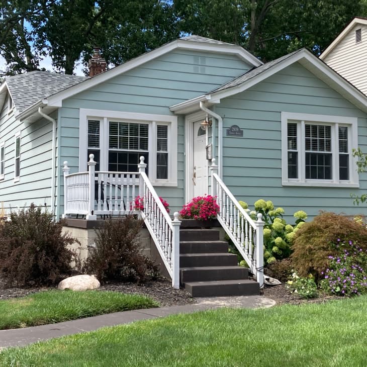 Exterior of a blue house with stairs leading up to the front door