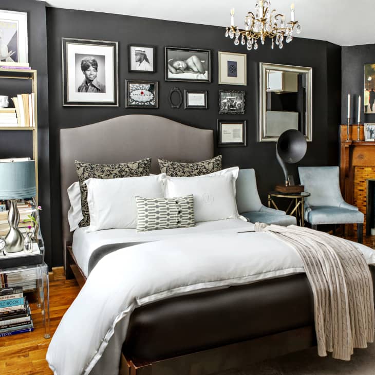 A gray bedroom with a wooden fireplace and framed art on the walls