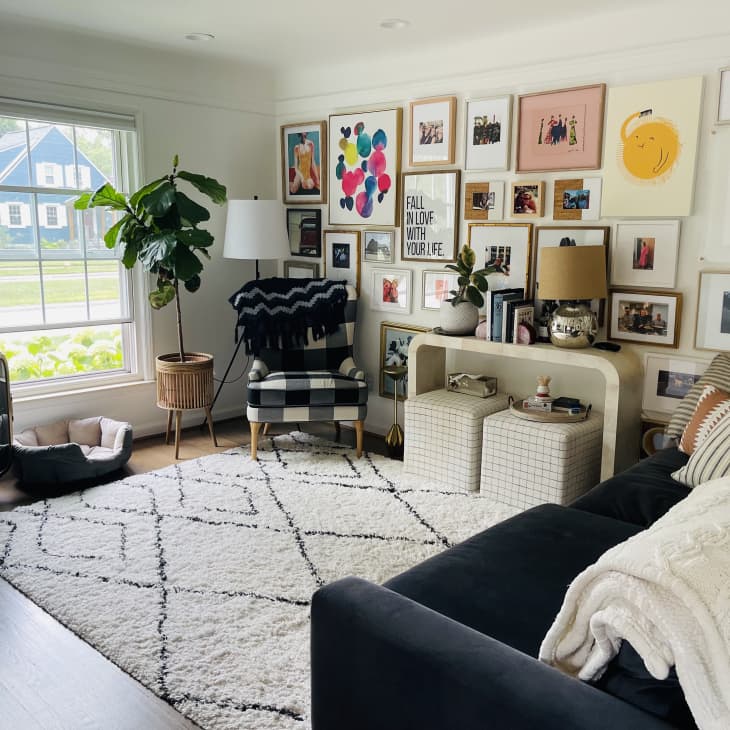 A large white living room with a large gallery wall and a blue couch