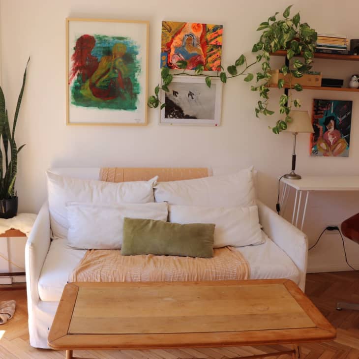 A white loveseat with pictures hanging above