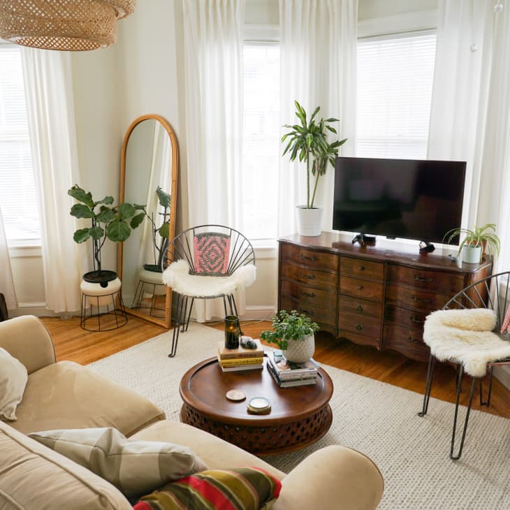 A living room with a tan couch, two chairs, and a tv