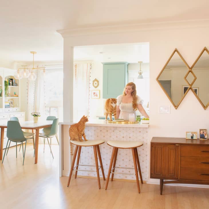 A woman at the kitchen counter wither her two orange cats