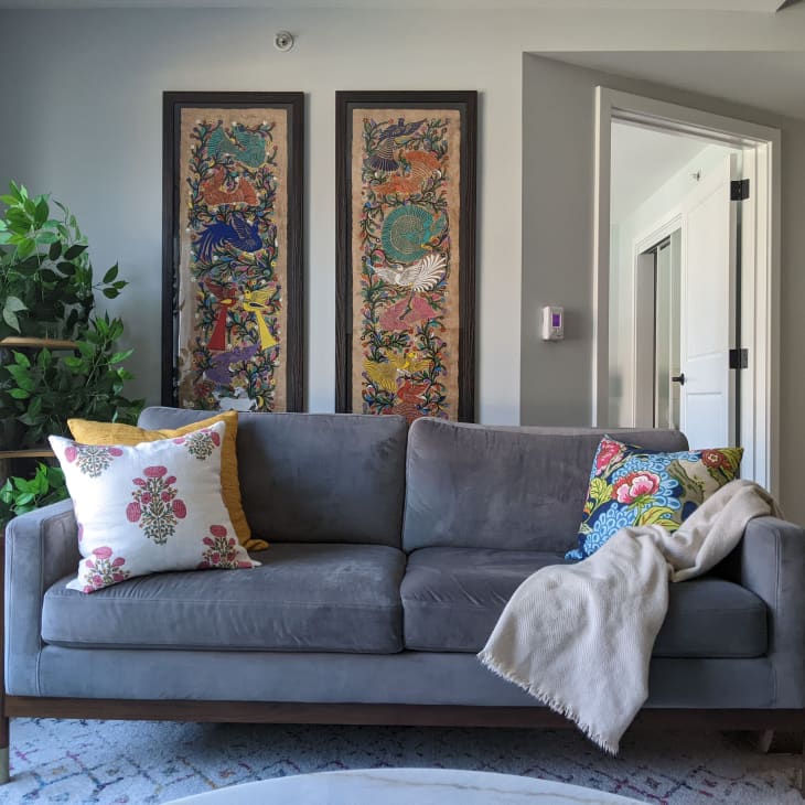 Grey microfiber sofa in living room. Two tapestries hang on wall in living room