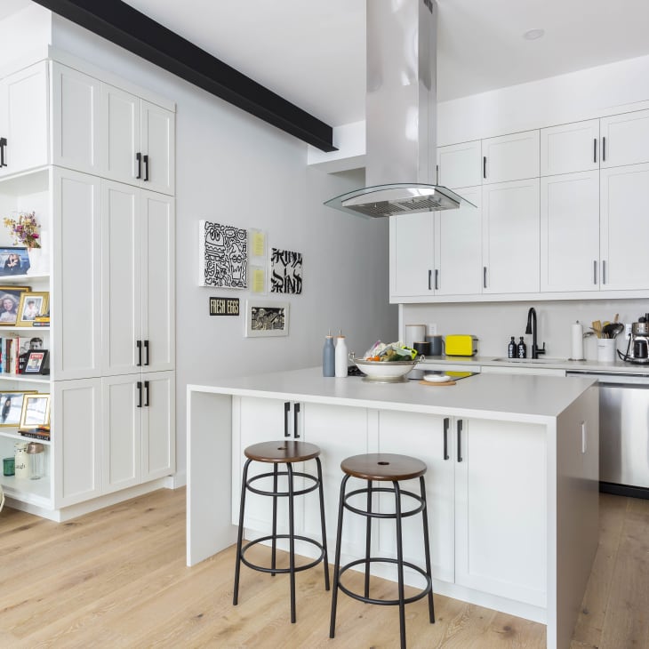 A kitchen with white cabinets and and island with two stools