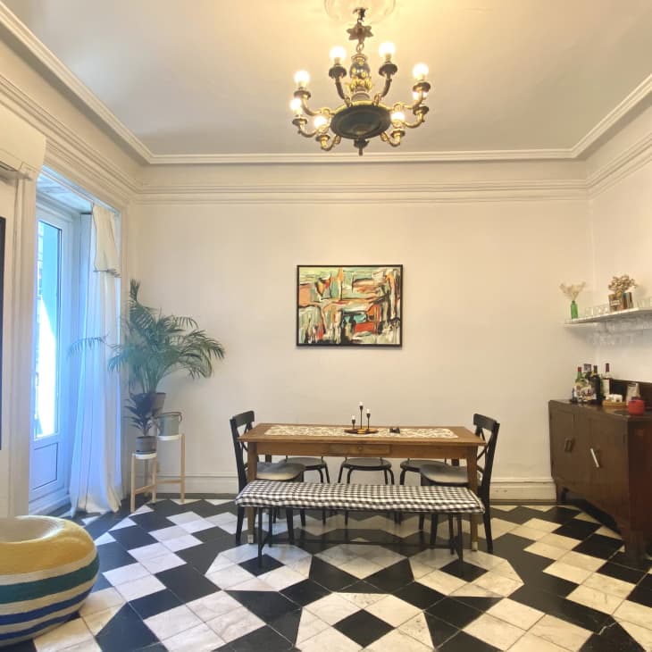 A dining table with five chairs and a bench on black and white tiled floors
