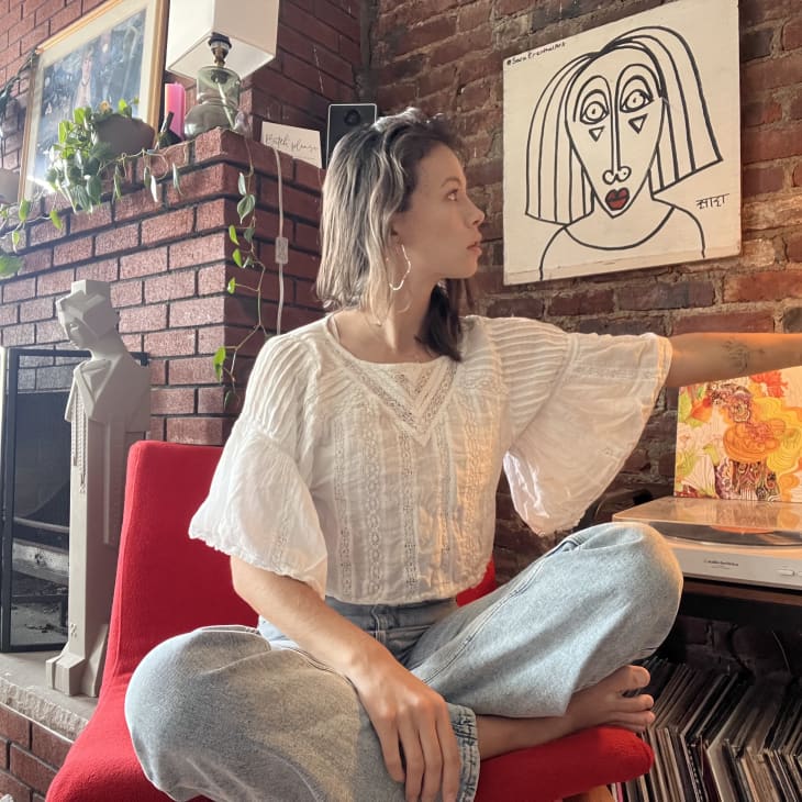 A woman sitting in a red chair in front of a brick wall