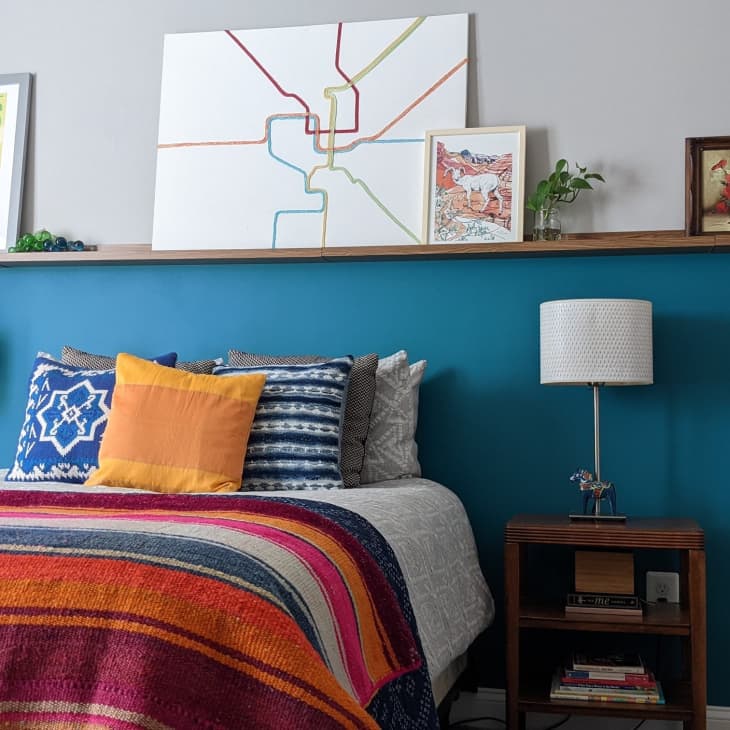 Bedroom with blue half wall and colorful bedspread.