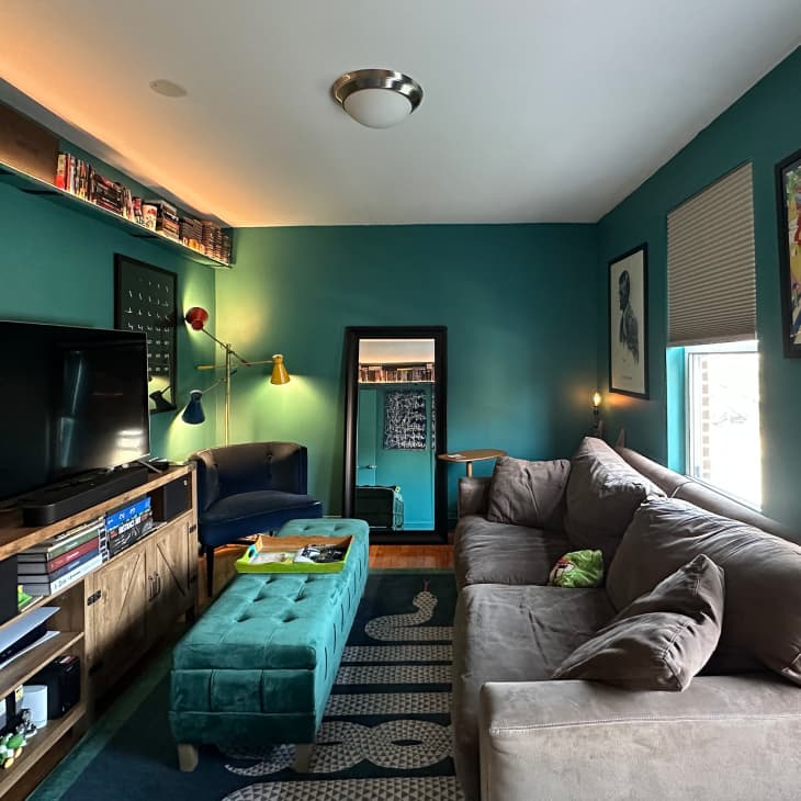 A blue-green living room with a gray couch facing the tv