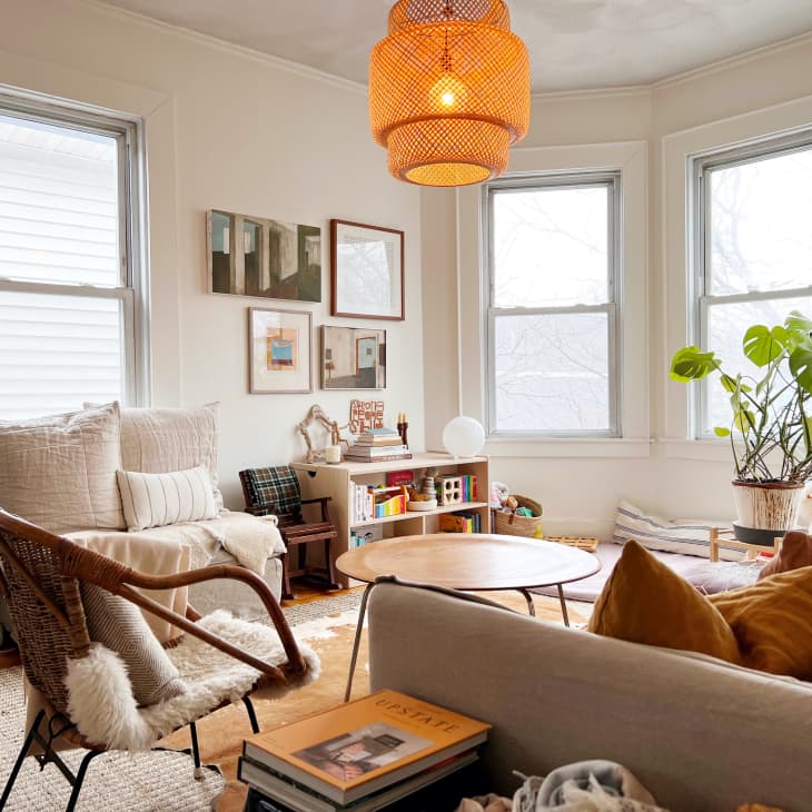 Living room with white walls, neutral textile furnishings, wood floor, round coffee table, plants, art