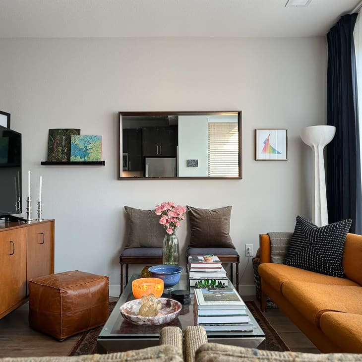 Living room in studio apartment with lots of vintage finds. The plaster floor lamp was sourced from @hutchandhardware. The collection of objects on the Crate & Barrel glass-top table include a ribbed green Murano glass vase sourced from Chairish and an onyx bowl from @_themodernheirloom.