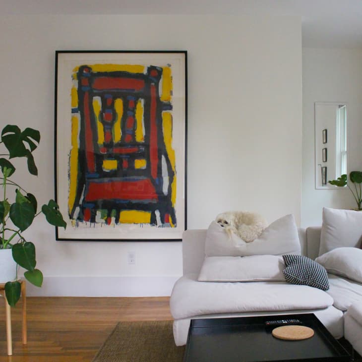Art print on wall in plant filled living room.