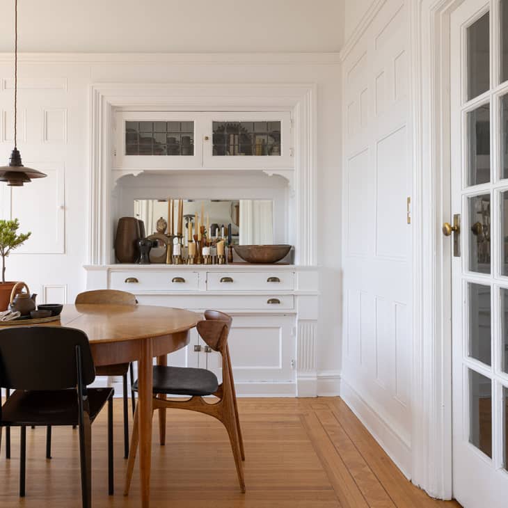 white dining room with built in cabinet and drawers, oval wood dining table and midcentury modern chairs