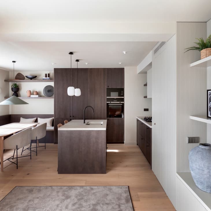 View into modern minimal white kitchen and dining room with dark brown kitchen island and cabinets