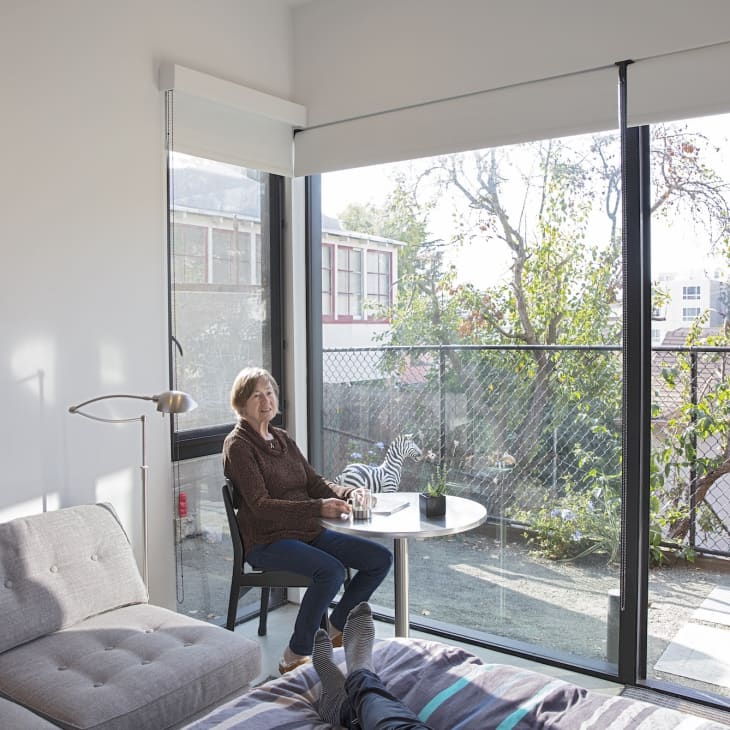 someone sitting in white living room of tiny home next to large windows