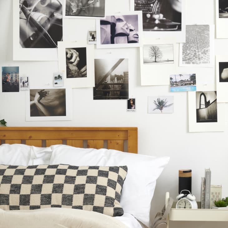 close shot of bed with checkered black and cream pillows and photos on the wall