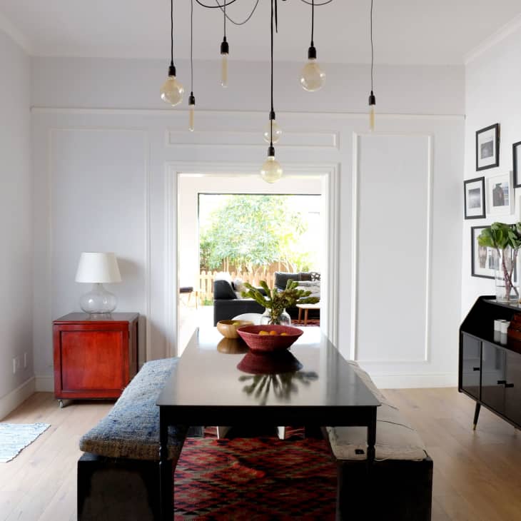 Dining room with black table, bench seating, pendant lights, red cabinet, and wall art gallery.