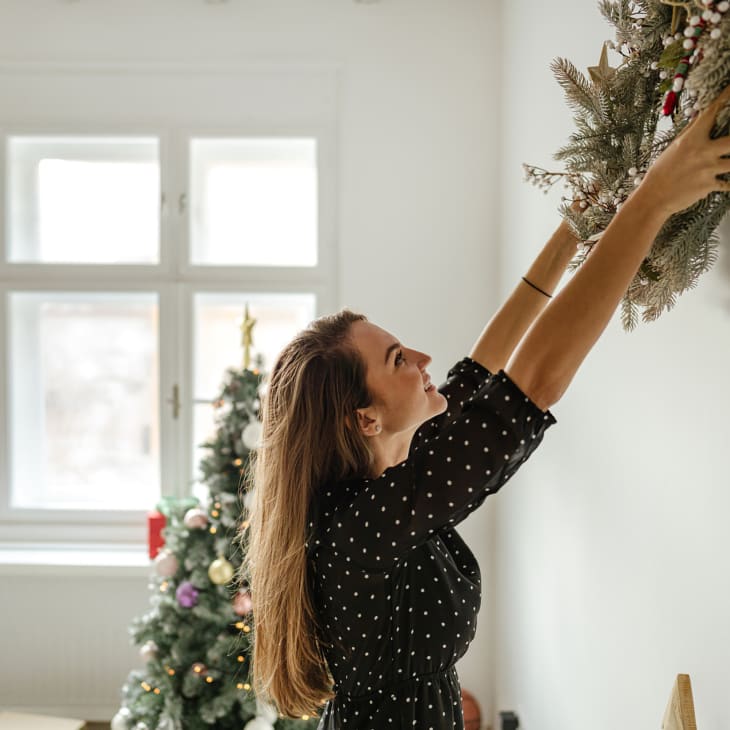 Young woman decorating her living room for the upcoming holidays