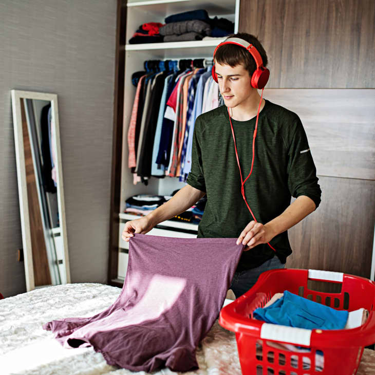 teenager boy wearing headphones, organizing clothes in his room