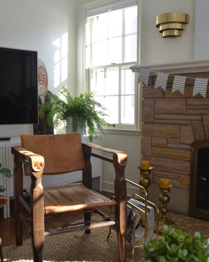 Wooden armchair in a cozy living room with a stone fireplace, potted plants, and a wall-mounted TV.