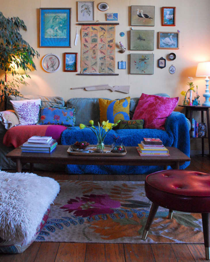 Cozy living room with colorful cushions, gallery wall, wooden coffee table, and a lamp on a side table.