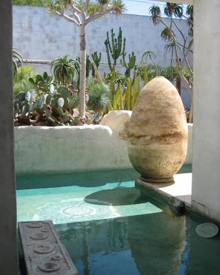 Outdoor courtyard with a large stone egg sculpture, cacti, and a turquoise pool.