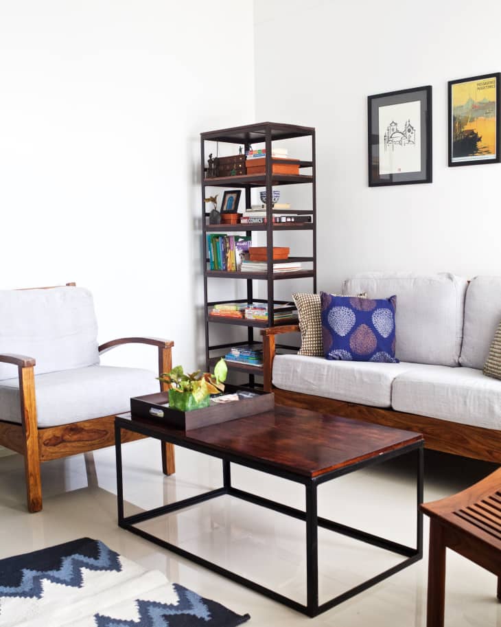 Living room with a wooden coffee table, gray sofa, armchair, bookshelf, and framed art on the wall.