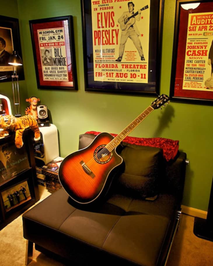 Cozy music room with framed concert posters, acoustic guitar on a black chair, and vinyl records on shelves.